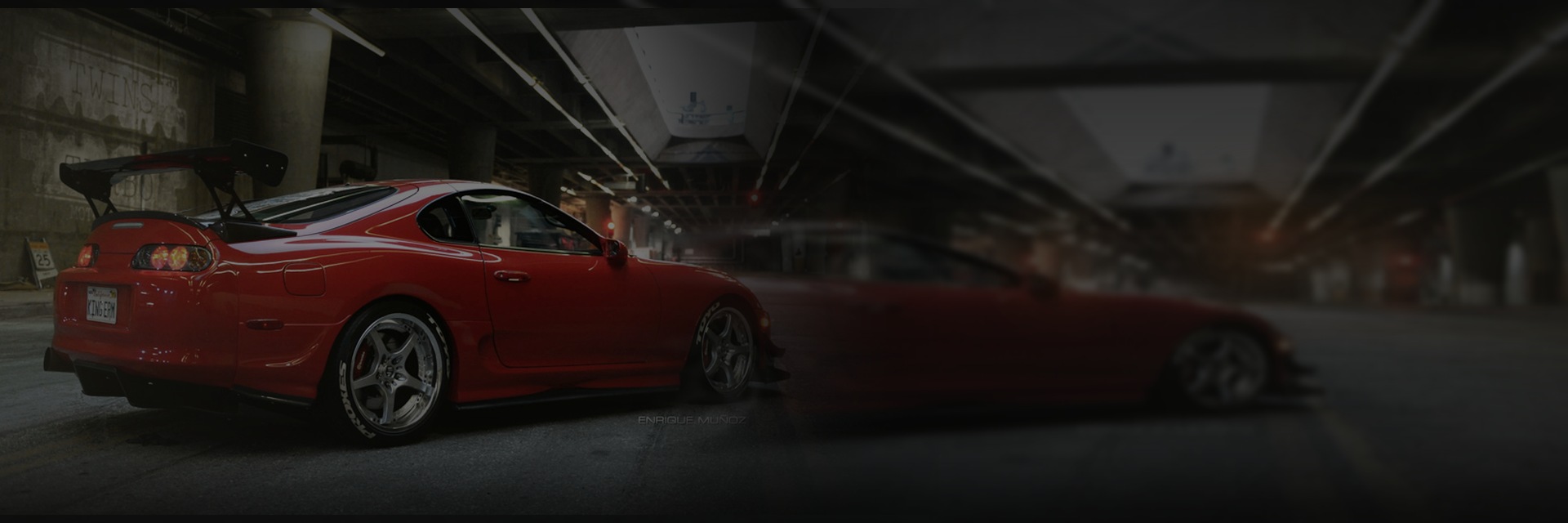 A red performance car beneath city overpasses at night